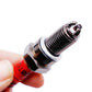 Motorcycle spark plug held in fingers; red insulator and threaded metal tip
