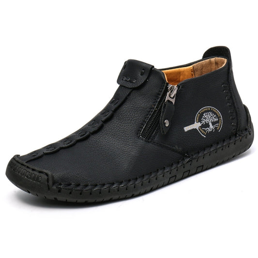 Men's ankle boots in black leather with side zipper, strap buckle, and stitched detailing