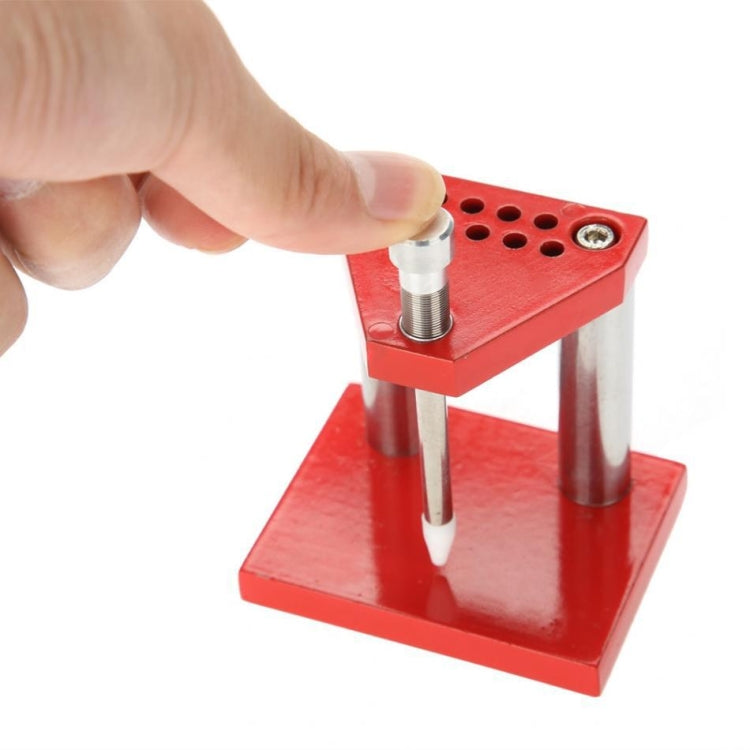 Watch hand plunger puller tool held by hand, red base with needle and metal posts