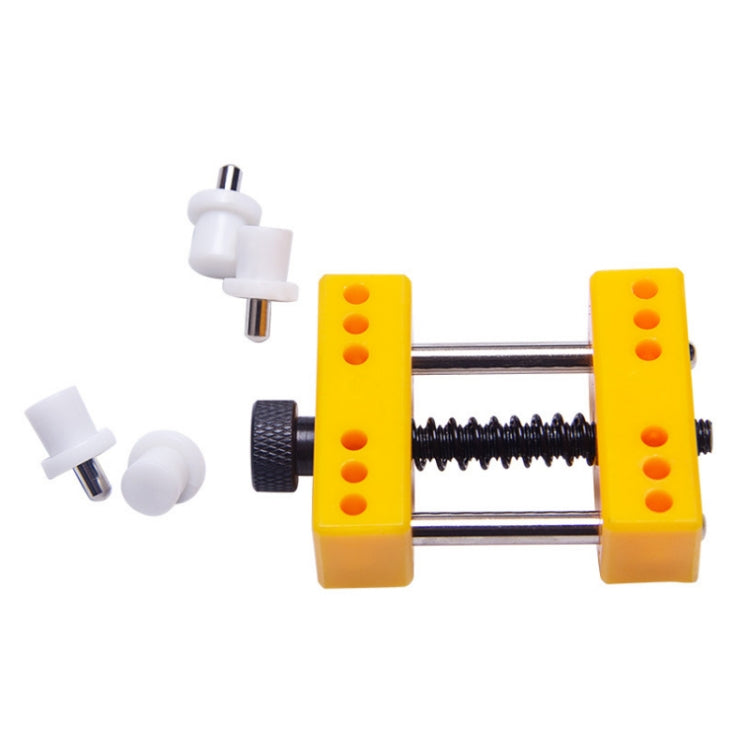Yellow watch repair clamp tool with metal bars, spring, and white guide pegs