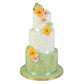 Tiered cake decorated with green tropical leaf fondant accents and flowers
