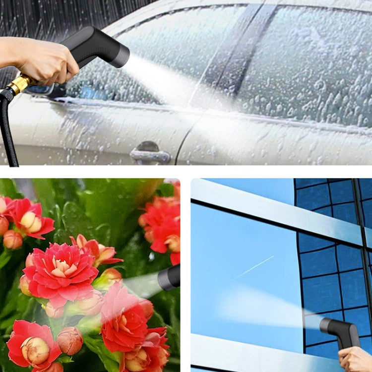 Hand using black sprinkler nozzle to spray water on cars, flowers, and building