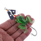 Soft frog fishing lure on a hand: green glitter body with spinner blade and hook