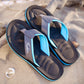 Pair of men's flip flops in dark gray with bright blue straps on sand