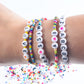 Beaded alphabet bracelets on wrist with white letter beads and colorful accents