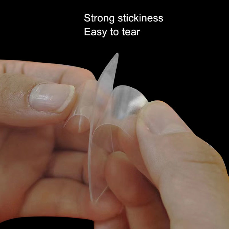 Clear double-sided tape sticker piece held between fingers, stretched thin