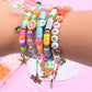 Stack of colorful beaded charm bracelets with star and shell pendants on a wrist