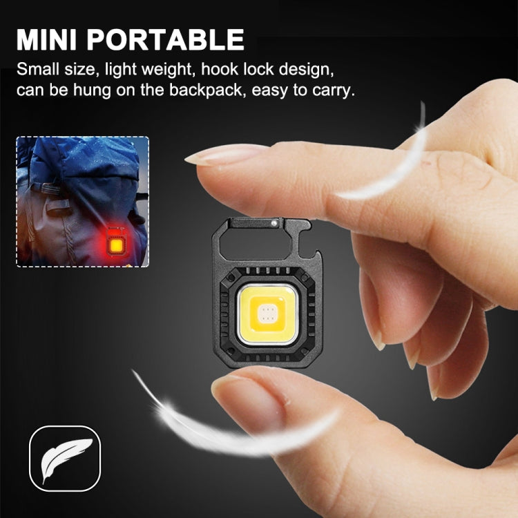 Black mini keychain flashlight with bracket, COB light head and red switch in hand