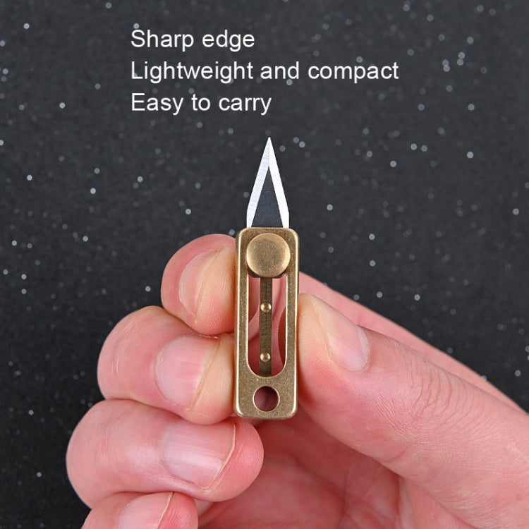 Hands holding brass mini push-pull knife pendant with blade extended