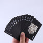 Hand holding a fan of black playing cards with gold numbers, suits, and court artwork