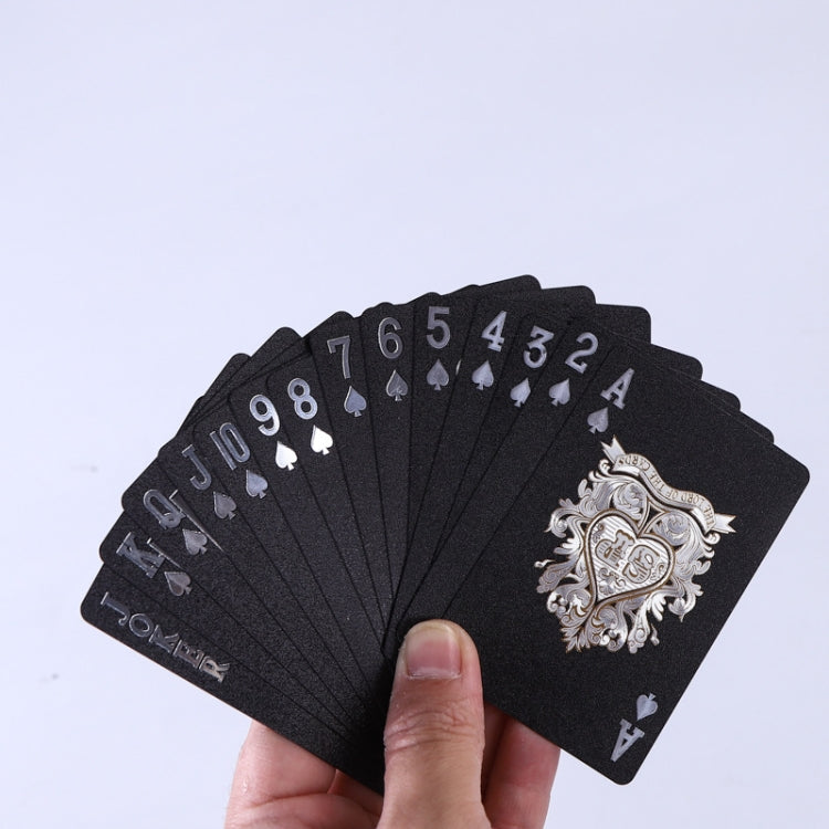 Hand holding a fan of black playing cards with gold numbers, suits, and court artwork