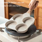 Four-cup egg pan on induction burner with wooden handle and speckled gray finish