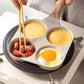 Four-hole egg frying pan with sunny-side-up eggs and sliced peppers in wells