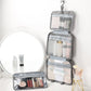 Gray foldable toiletry bag open with detachable inner pouch and clear zip compartments