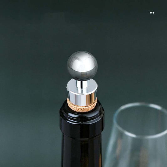 Metal wine stopper with cork insert and rounded chrome head on bottle neck