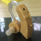 Tan hearing aid device with clear earhook tube and side control label