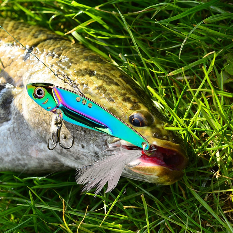 Iridescent blue and purple fishing lure lying on grass with white feather skirt