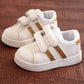 Children's white sneakers with gold side stripes and double hook-and-loop straps, pair