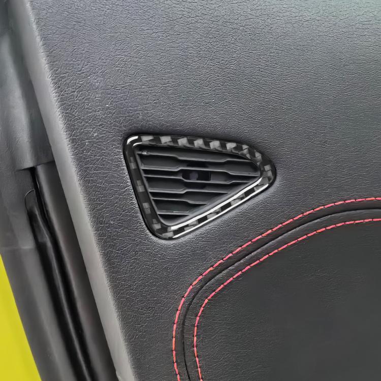 Close-up of installed black carbon-fiber door air vent trim sticker with red stitching edge