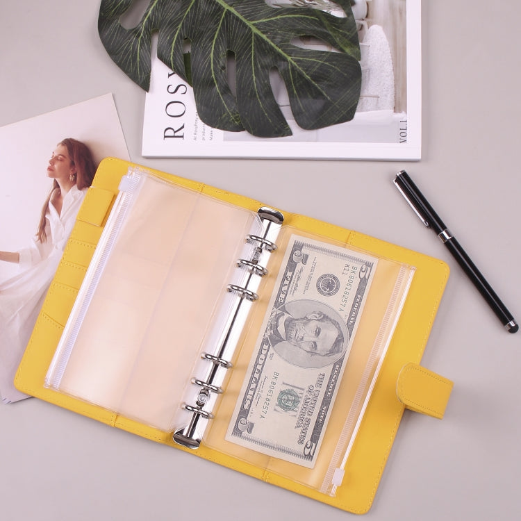 Yellow cash budget notebook open with cash, clear pocket sleeves, and stainless-steel rings