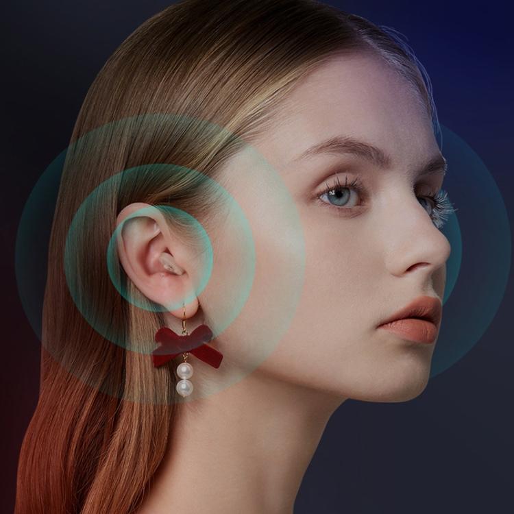 Behind-the-ear digital hearing aid with clear earpiece worn on model's ear