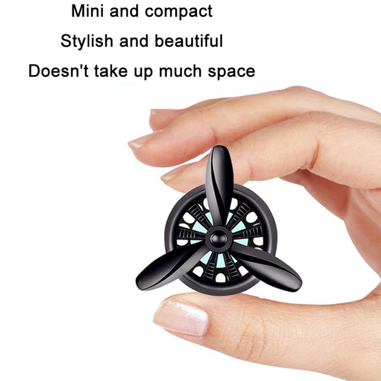 Mini car air outlet perfume swivel fan, black propeller with central hub held in hand