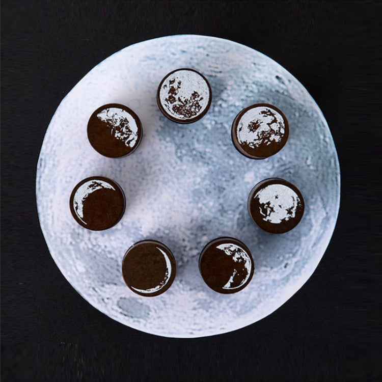 Round moon phase wooden stamps on a tray: brown discs with white crater moon details