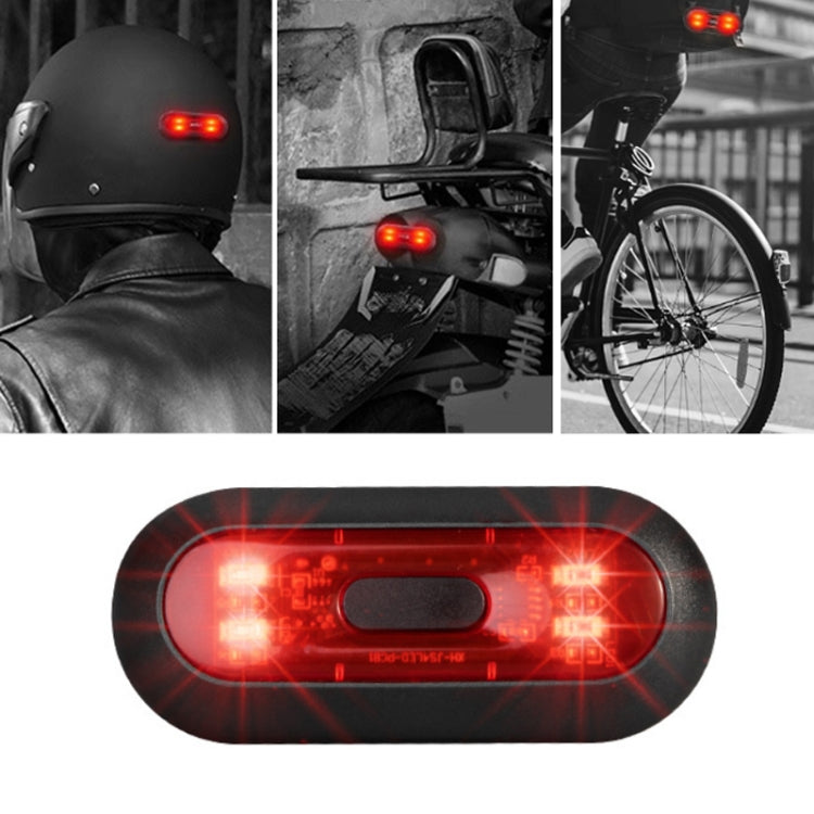 Motorbike helmet tail light, black housing with red glowing LED strips, close-up.