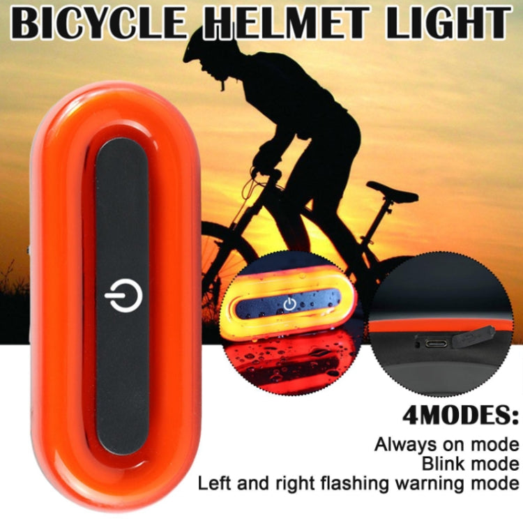 Orange bike helmet tail light with red LED glow and visible mounting strap