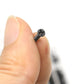 Black Phillips-head laptop screw close-up held between fingertips