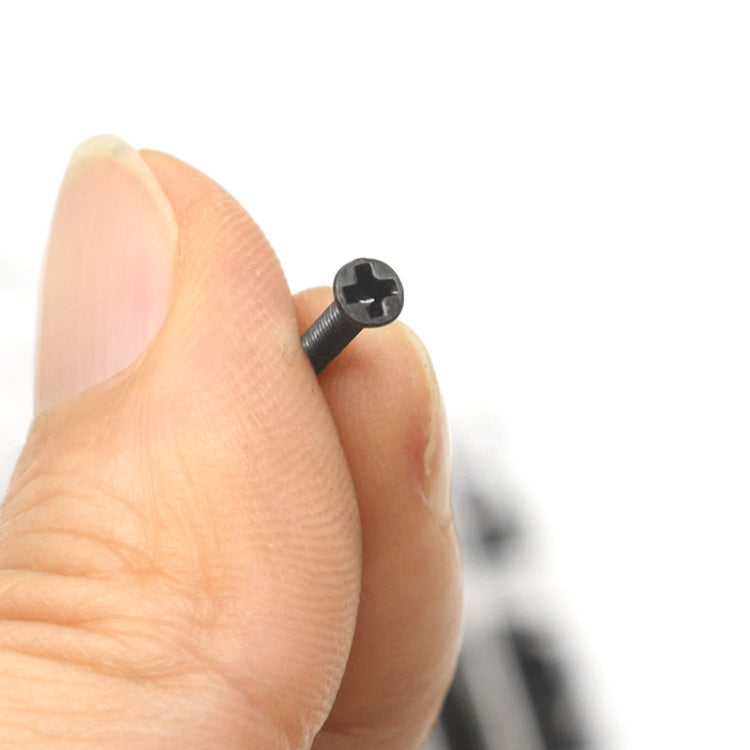 Black Phillips-head laptop screw close-up held between fingertips