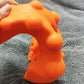 Orange acupressure massager close-up with raised dome nodes and ridged grips