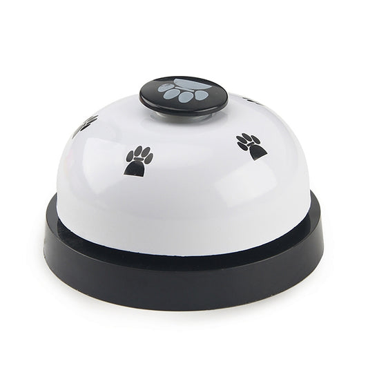 White dog training bell with black paw-print button and round base.
