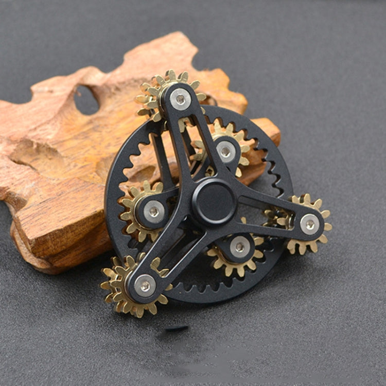 Four-gear fidget spinner with black body and gold-tone gears, ring of gear teeth.