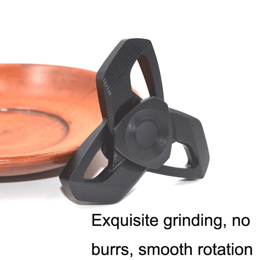 Black metal hand spinner on fingertip, three-armed design with circular core