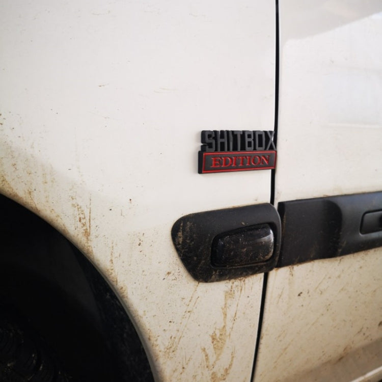 Small SHITBOX EDITION rear badge mounted on a car door panel