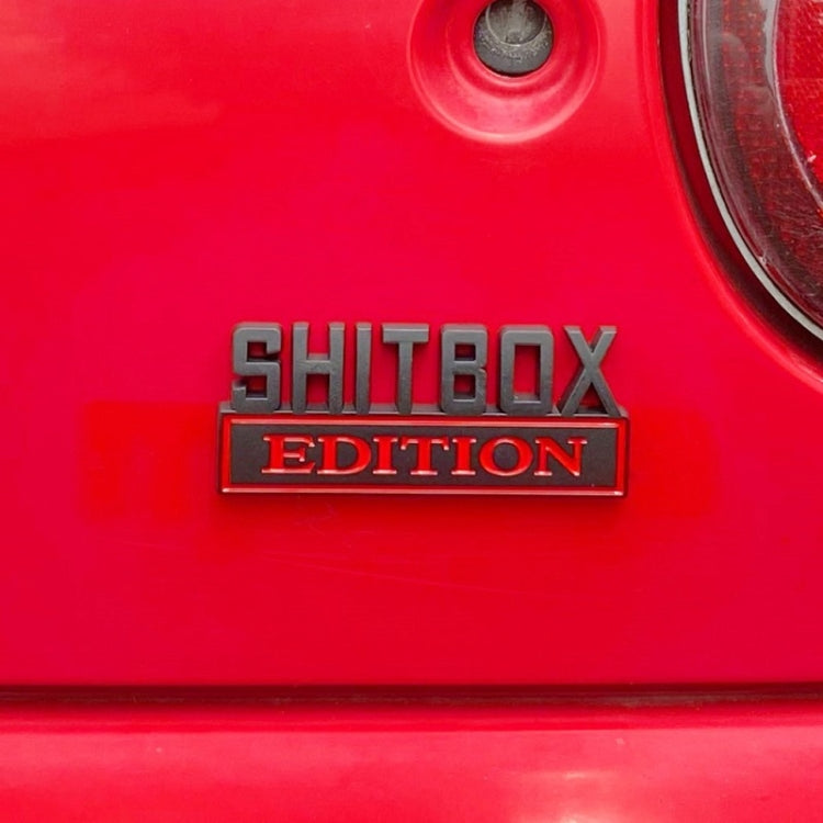 SHITBOX EDITION rear badge mounted on a red car body panel
