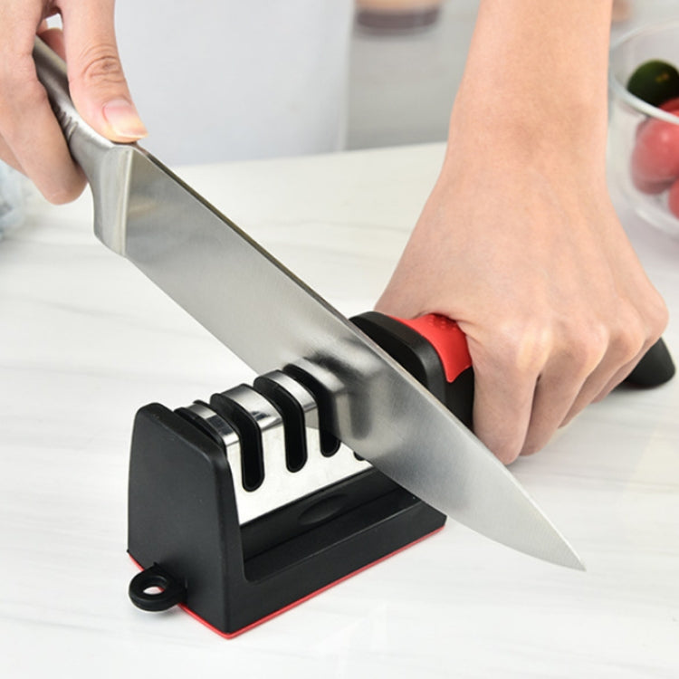 Handheld knife sharpener in use with a knife blade positioned in the slots