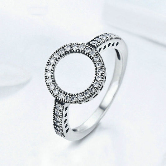 Silver-tone circular halo ring with clear stones and side cutout details