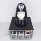 Coffee capsule holder drawer with black top and front wire tray holding multicolor pods