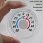 Handheld view of round plastic thermometer with °C scale and colored indicator ring