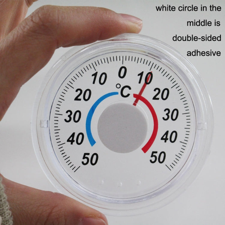 Handheld view of round plastic thermometer with °C scale and colored indicator ring