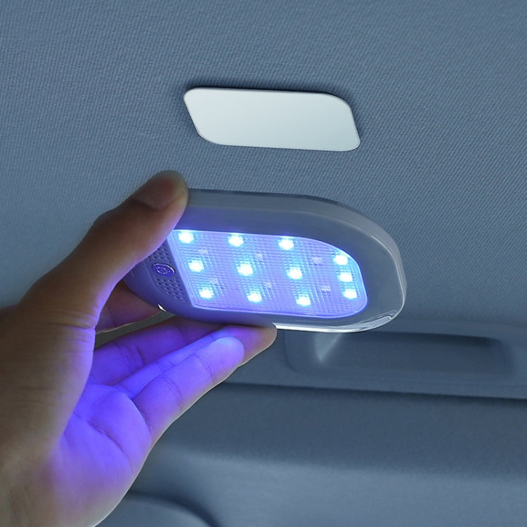 Hand holding a blue magnetic LED reading light mounted on a car ceiling
