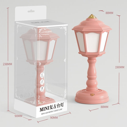 Pink retro table lamp with lantern-style shade, turned stem, and round base.