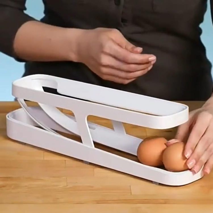White two-tier egg holder with open top, showing an egg being placed by hand