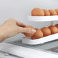 White egg dispenser tray with rolling track, showing a hand placing an egg