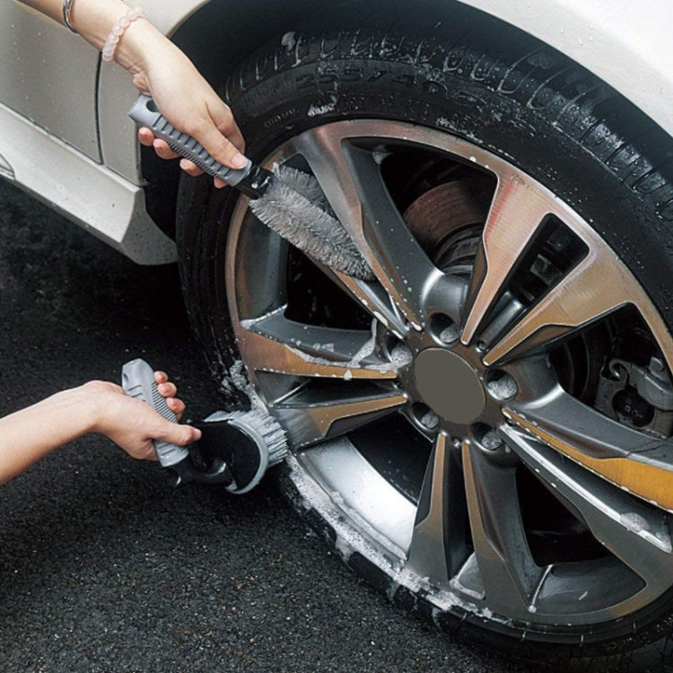 Hand using gray microfiber wheel brush to scrub alloy tire spokes