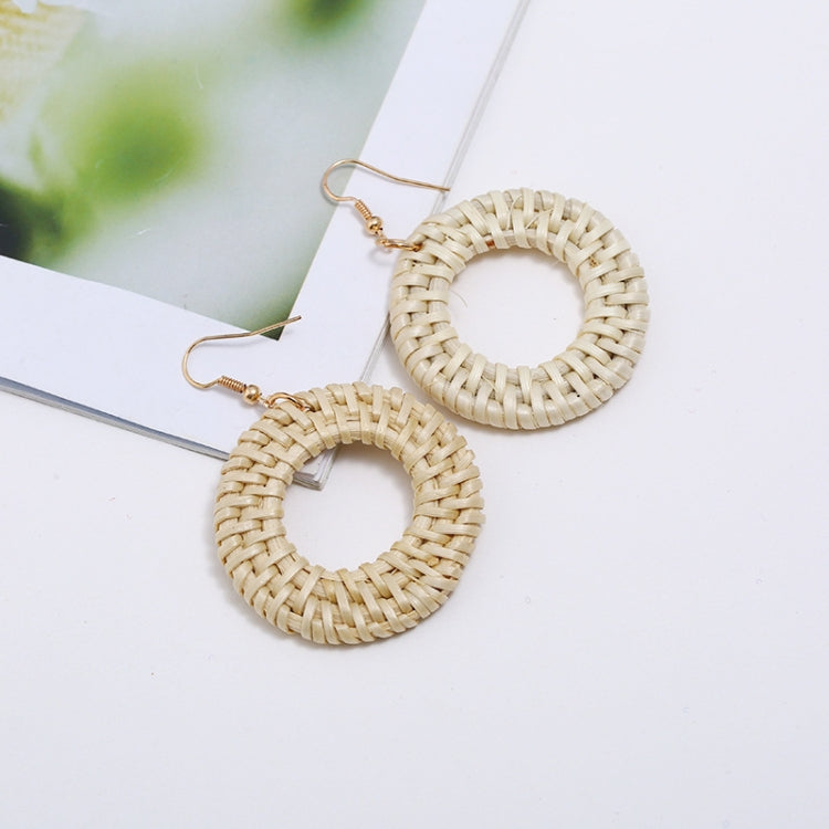 Handmade woven circular hoop earrings with gold-tone ear hooks, natural beige fiber.