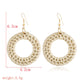 Handmade woven circular hoop earrings with gold-tone ear hooks, natural beige fiber.