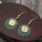 Sunflower drop earrings with teal patterned round discs, gold flower centers, and beaded drops